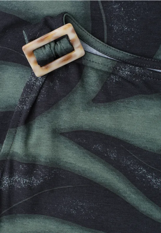 Close-up van olijfgroene stof met donker camouflagepatroon en een vierkante lichte gesp.