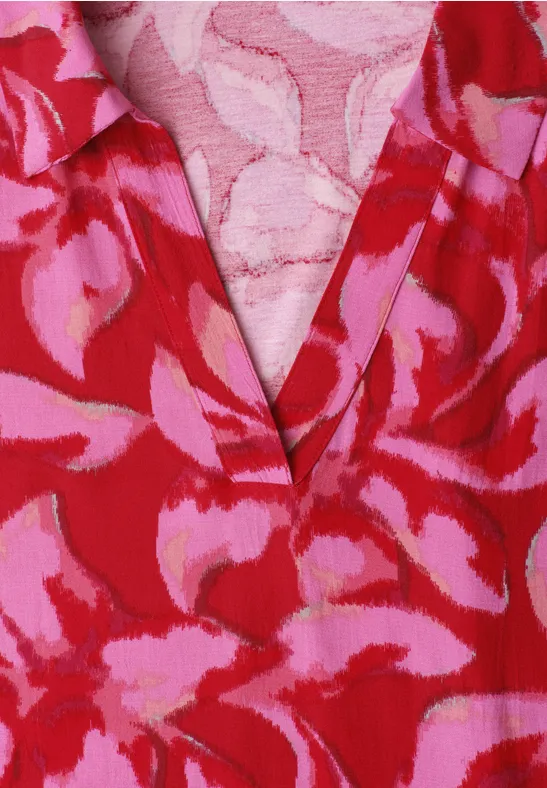 Haut rouge à motifs floraux roses avec encolure en V.