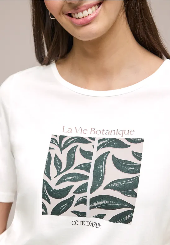 Weißes T-Shirt mit stilisiertem Blattmuster und Schriftzug „La Vie Botanique COTE D'AZUR“.
