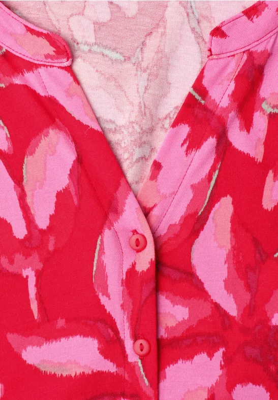 Nahaufnahme eines rot-pinken gemusterten Gewebes mit Knopfleiste