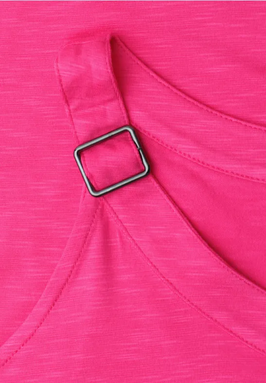 Close-up van een roze top met bandje en zilverkleurige gesp.