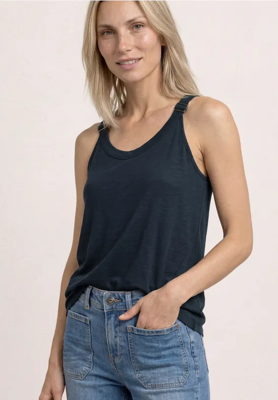 Vrouw draagt losse donkerblau tanktop en lichtblauwe jeans.