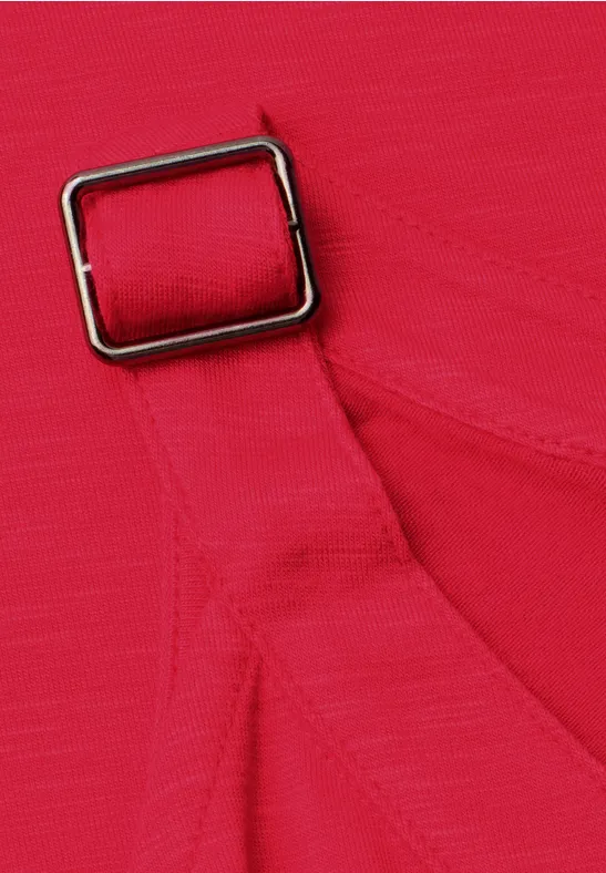 Close-up van een felroze stoffen band met een rechthoekige metalen gesp.