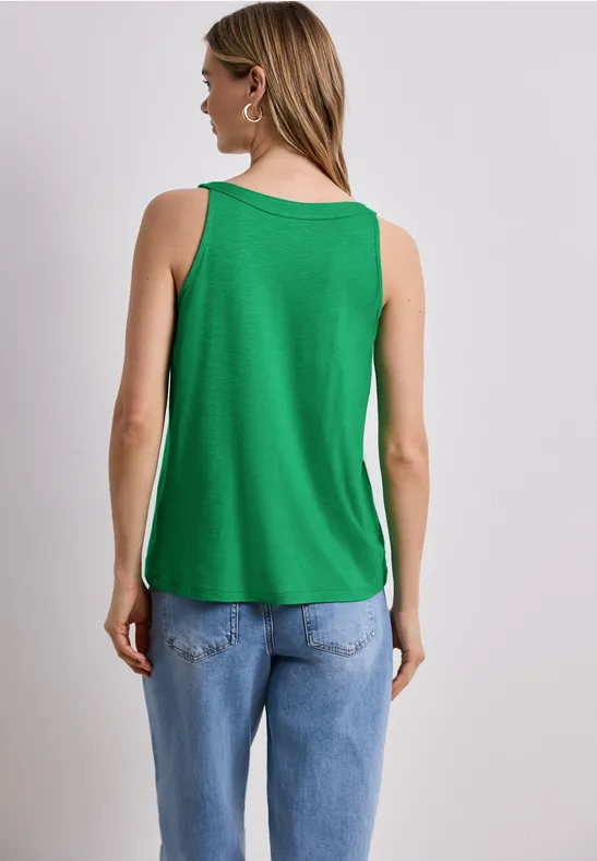 Vrouw van achteren met groen mouwloos shirt en blauwe spijkerbroek.