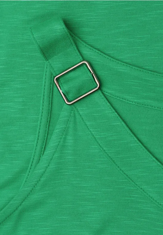 Close-up van groene stof met verstelbare band en zilverkleurige rechthoekige gesp.