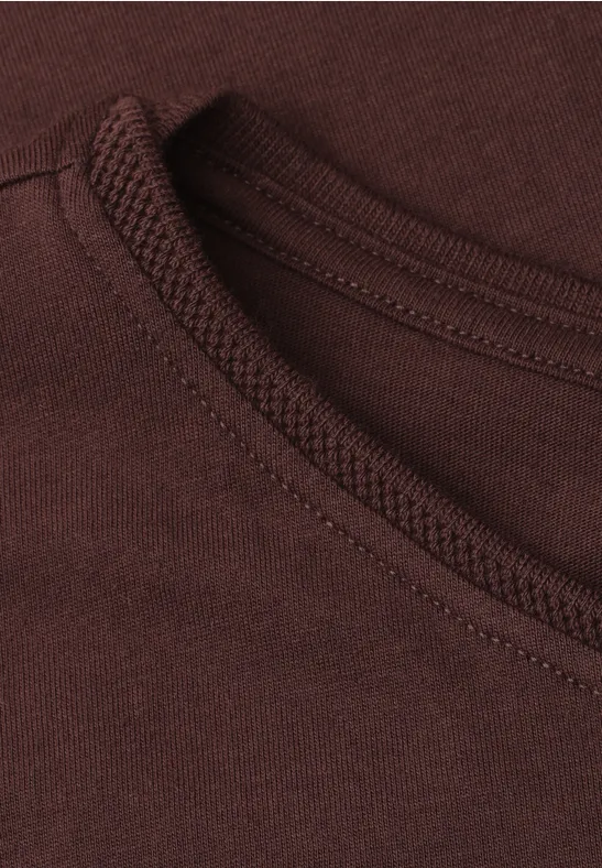 Gros plan sur l'encolure d'un t-shirt marron avec surpiqûres apparentes