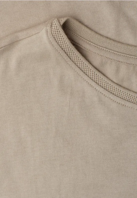 Nahaufnahme eines beigen T-Shirt-Ausschnitts mit sichtbarer Naht.