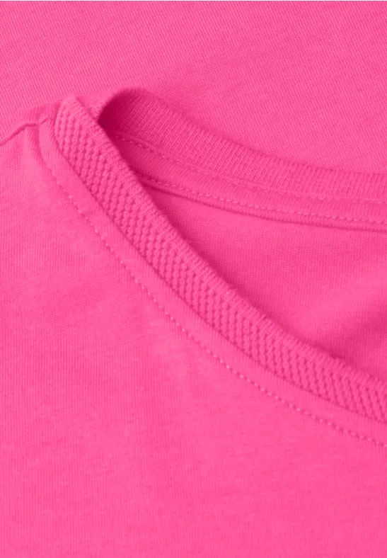 Close-up van een felroze T-shirtnek met zichtbare stiknaden en zachte katoenen stof.