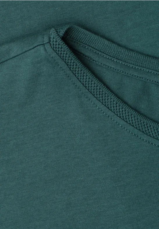 Close-up van een donkergroen T-shirt met zichtbare stiksels bij de ronde hals.