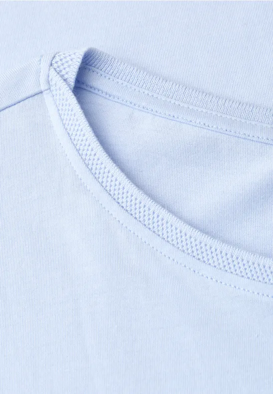 Close-up van de ronde hals van een lichtblauw t-shirt.