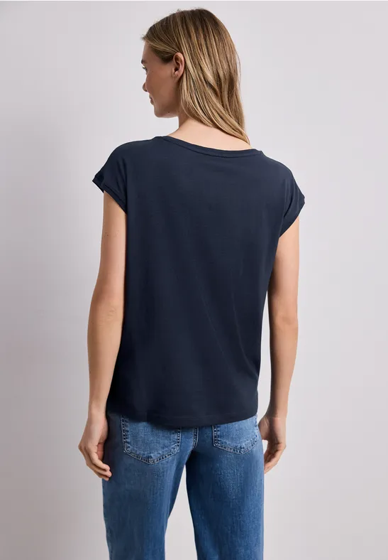 Vrouw van achteren in een zwart t-shirt en blauwe jeans voor een neutrale achtergrond