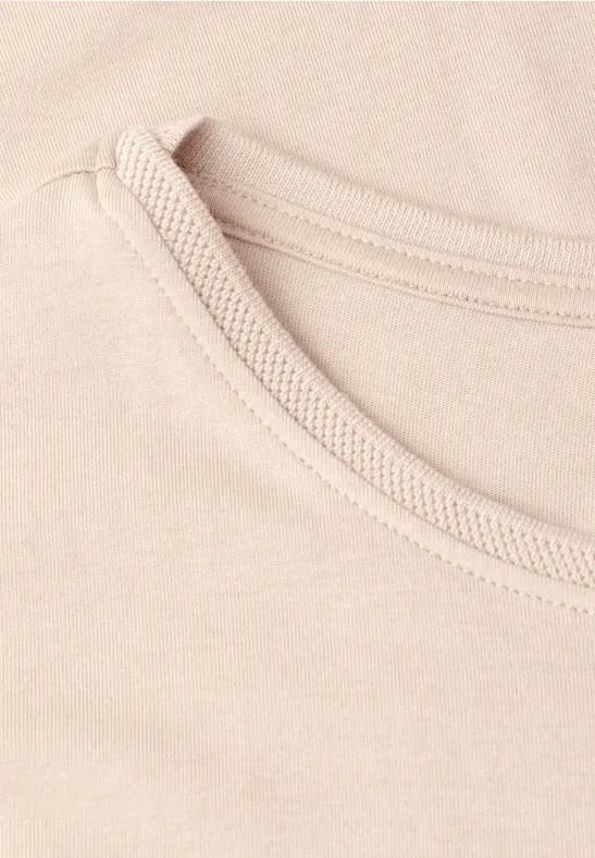 Close-up van een lichtbeige ronde hals van een T-shirt.