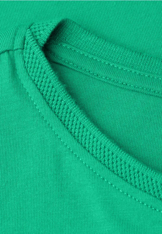 Close-up van een groene T-shirthals met versterkte naad