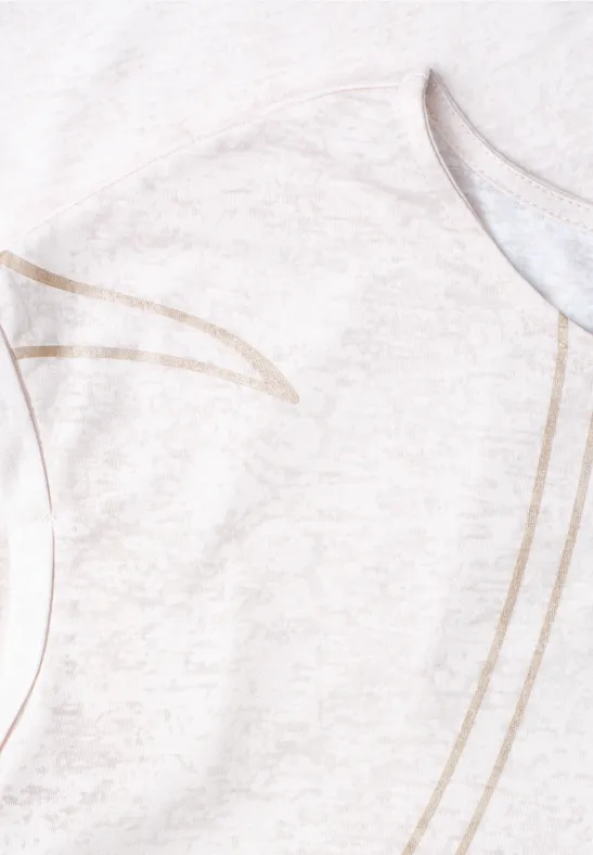 Gros plan d’un t-shirt clair avec motif de lignes dorées délicates sur un tissu doux.