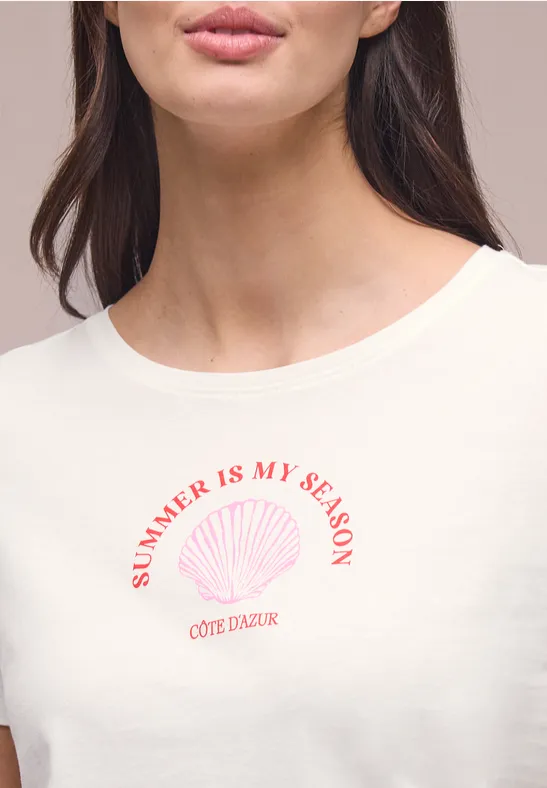Close-up van een vrouw in een wit t-shirt met 'SUMMER IS MY SEASON'-tekst en schelpmotief.