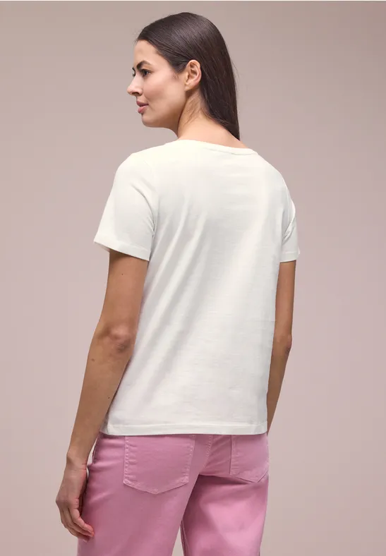 Vrouw gezien van achteren met een wit T-shirt en een roze broek.