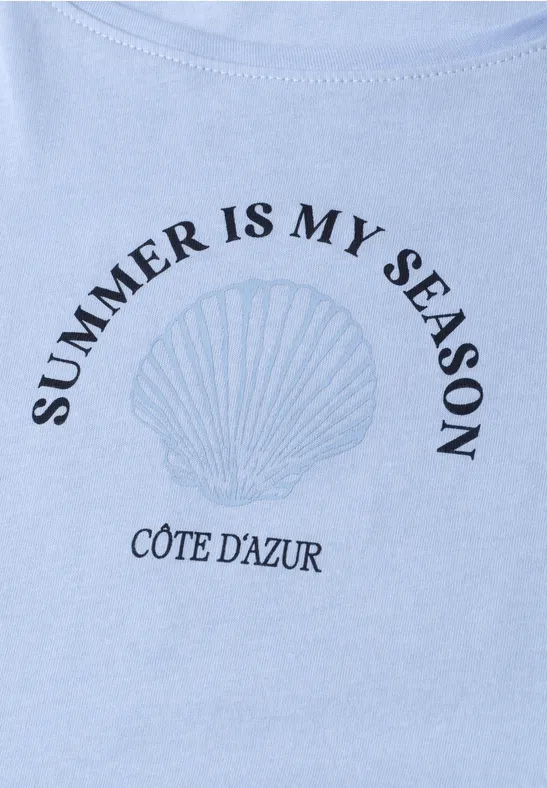 Lichtblauw T-shirt met schelpafbeelding en teksten 'Summer is my season' en 'Côte d'Azur'.