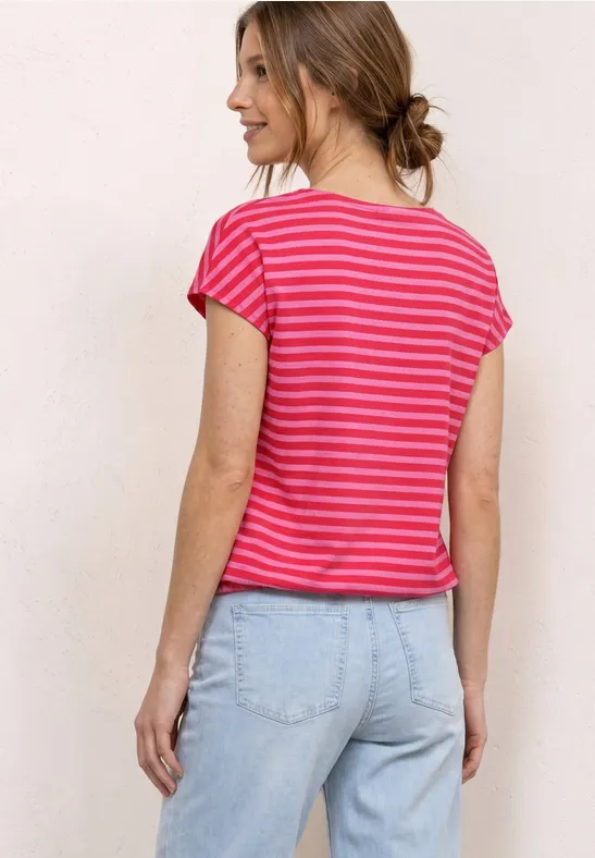 Vrouw van achteren in een roze-wit gestreept T-shirt en lichtblauwe jeans.