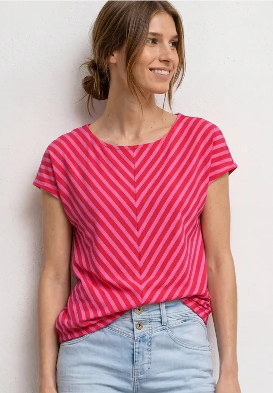 Vrouw in roze-rood gestreept T-shirt en spijkerbroek voor witte achtergrond.