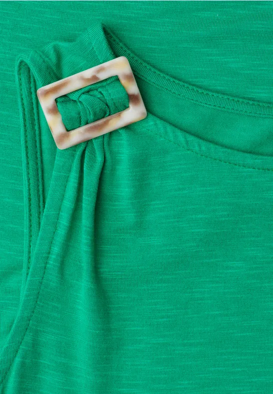 Groene stoffen band met een vierkante, lichte gesp op de schouder.