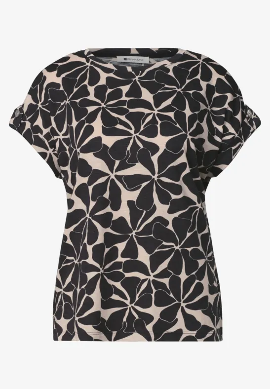 Beige shirt met losse pasvorm en zwart bloemenpatroon.