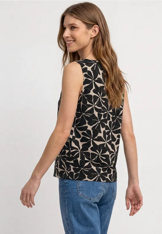 Frau von hinten in blauer Jeans und schwarzem, ärmellosem Top mit weißem, geometrischem Sternmuster.