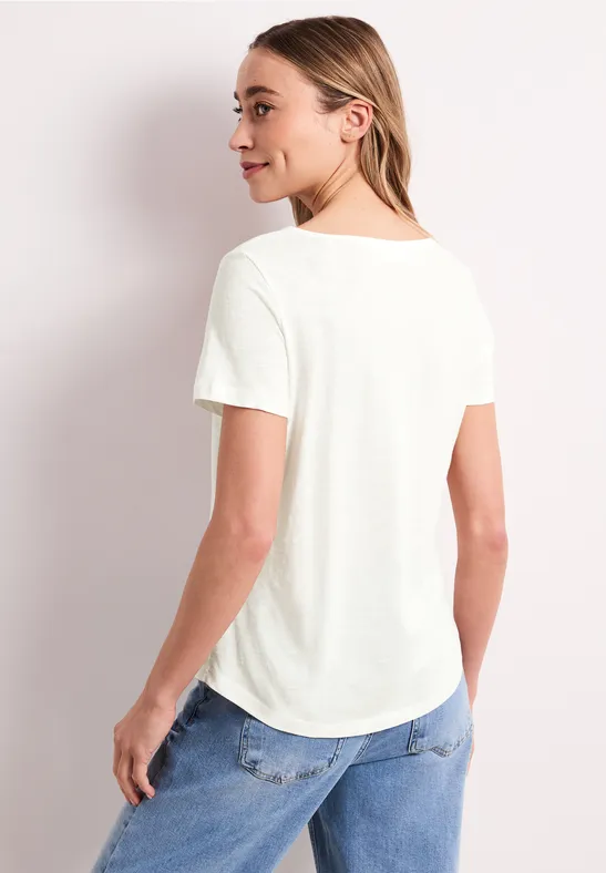 Rugaanzicht van een persoon in een wit T-shirt en blauwe spijkerbroek tegen een lichte achtergrond.