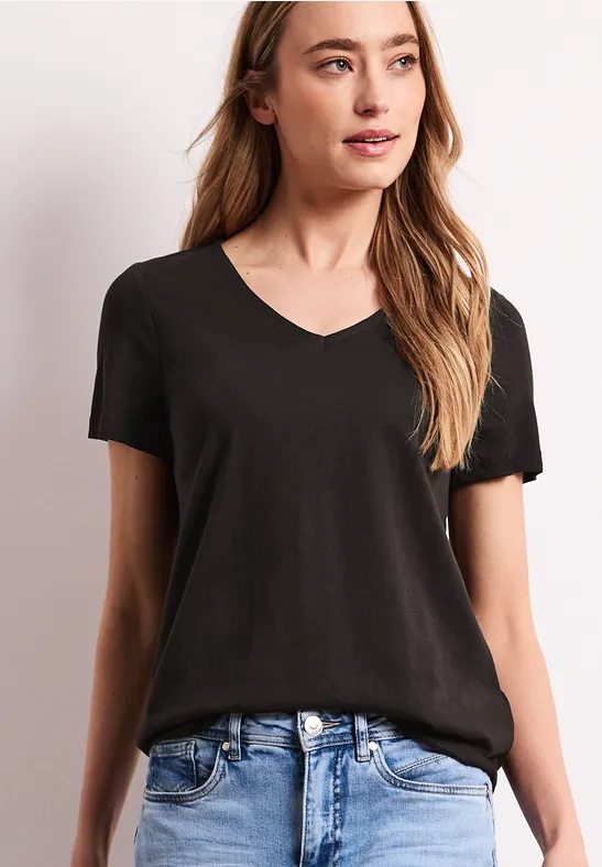 T-shirt noir à col en V à manches courtes, porté avec un jean bleu.