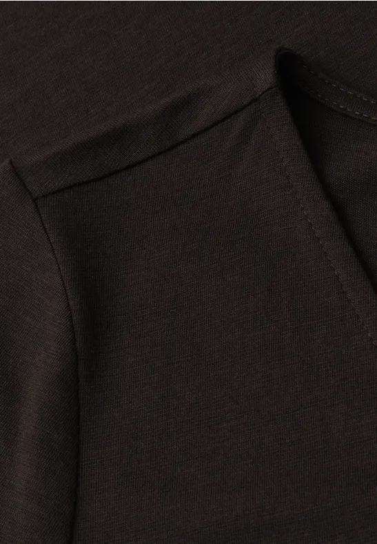 Gros plan sur un vêtement sombre avec couture et encolure visibles