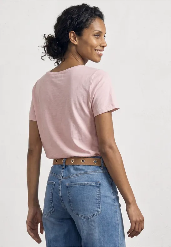 Frau von hinten in rosa T-Shirt und blauen Jeans mit Ledergürtel.