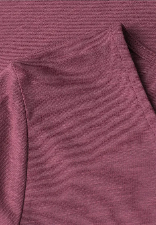 Close-up van een bordeauxkleurige jerseystof met fijne structuur en schoudernaden.