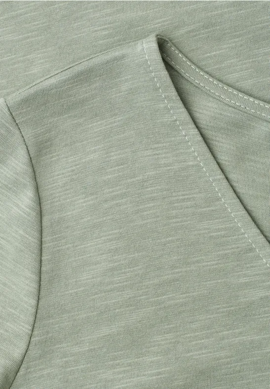 Nahaufnahme eines hellgrünen T-Shirts mit V-Ausschnitt und feiner, melierter Struktur.