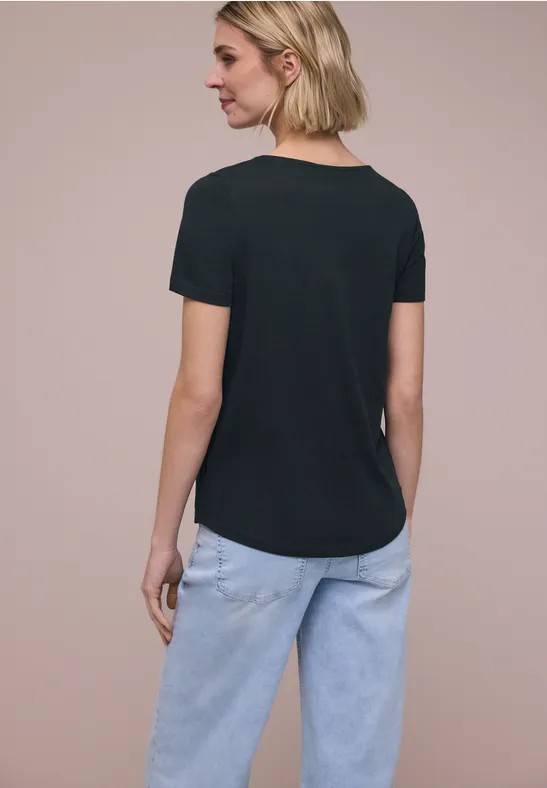 Vrouw van achter in zwart t-shirt en lichtblauwe spijkerbroek.