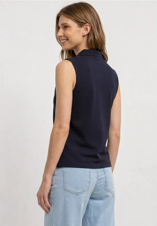 Frau in schwarzem ärmellosem Rollkragenpullover von hinten, trägt helle Jeans.
