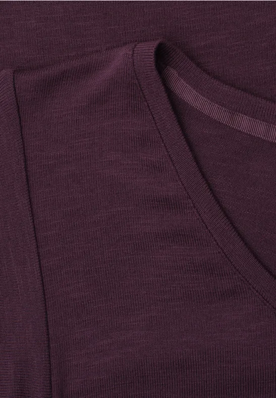 Nahaufnahme eines dunkelvioletten T-Shirts mit Rundhalsausschnitt und erkennbarer Schulternaht.
