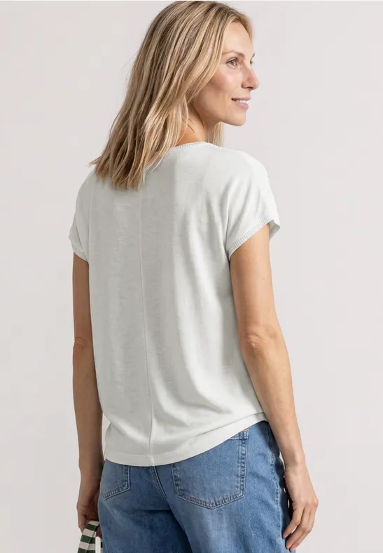 Vue de dos d'une femme aux cheveux blonds portant un t-shirt clair et un jean bleu.