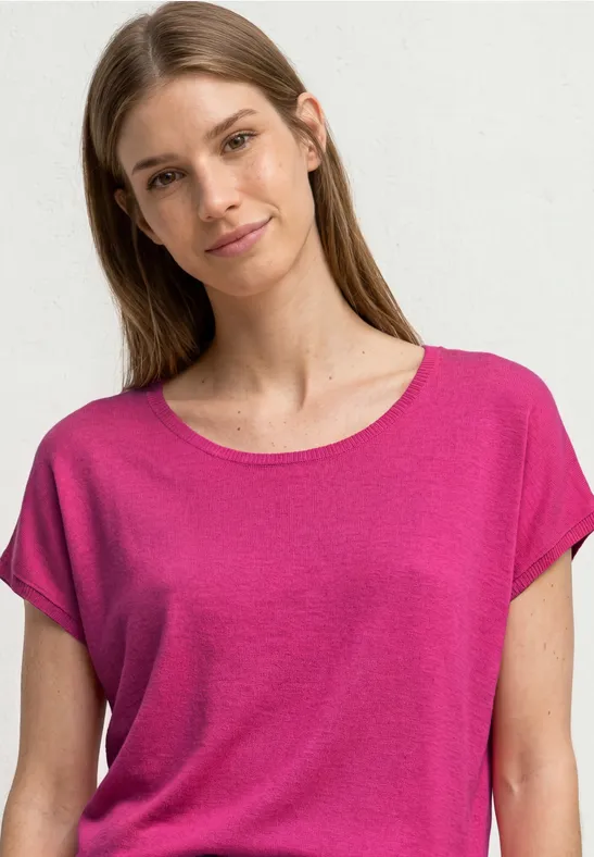 Een vrouw in een roze t-shirt voor een witte achtergrond.