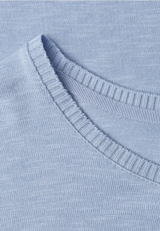 Nahaufnahme eines hellblauen Strickoberteils mit Rundhalsausschnitt und feiner Rippenstruktur.