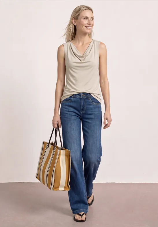 Dame in Jeans und ärmellosem Top trägt gestreifte Stofftasche