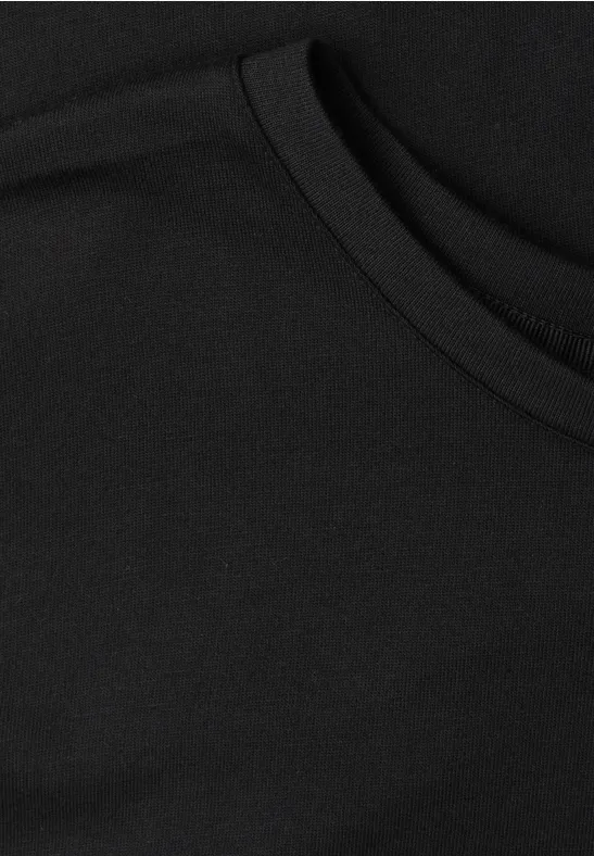 Zwarte stof met een afgeronde zakopening, waarschijnlijk een borstzakje van een T-shirt.