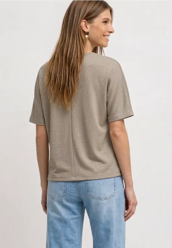 Vrouw van achteren in beige T-shirt en blauwe spijkerbroek.