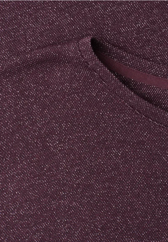 Nahaufnahme eines bordeauxfarbenen Strickstoffs mit Glitzereffekt und aufgesetzter Tasche.