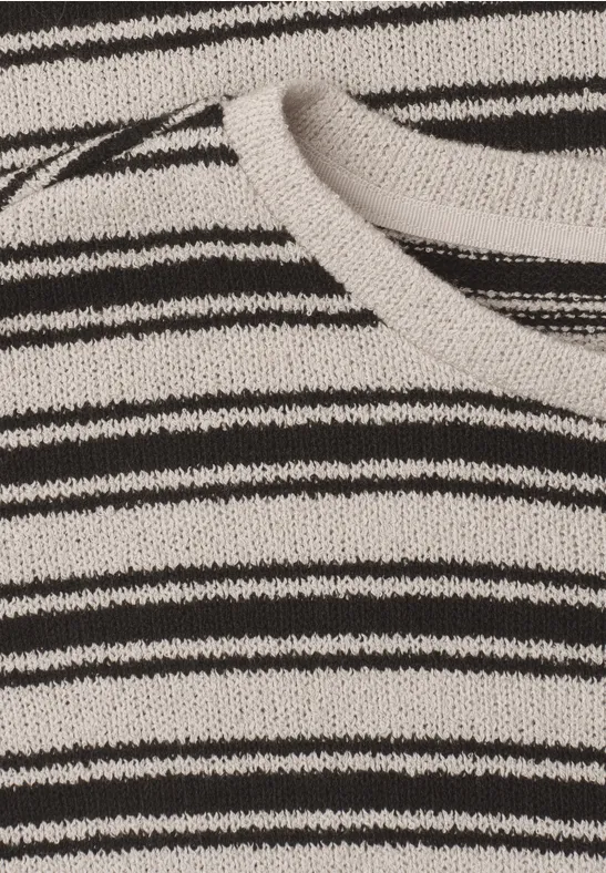 Nahaufnahme eines gestrickten Stoffs mit unregelmäßigen schwarz-weißen Querstreifen.