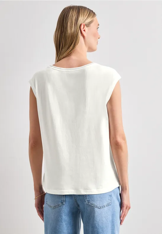 Achteraanzicht van een persoon in een los wit T-shirt met overhangende mouwen en een blauwe jeans voor een grijze achtergrond.