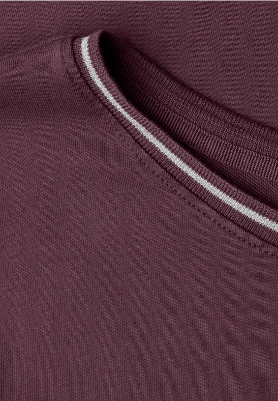 Close-up van een bordeauxrode T-shirt-halslijn met een subtiele, lichte stikseldetail.