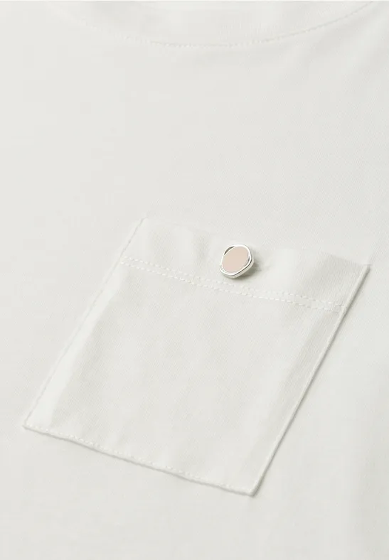Weißes T-Shirt mit Brusttasche und kleinem rundem Anstecker in Rosé an der Tasche vorne.