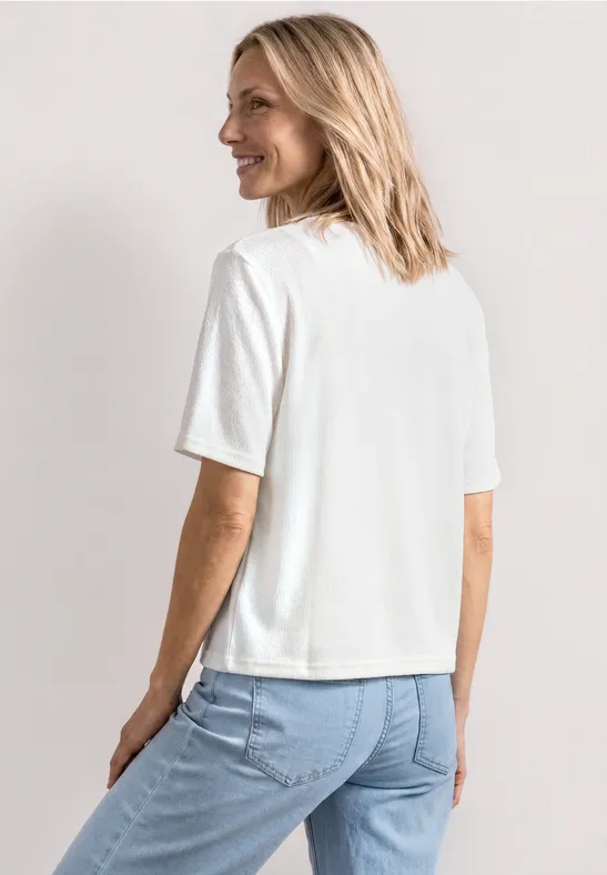 Frau von hinten in weißem T-Shirt und blauer Jeans.