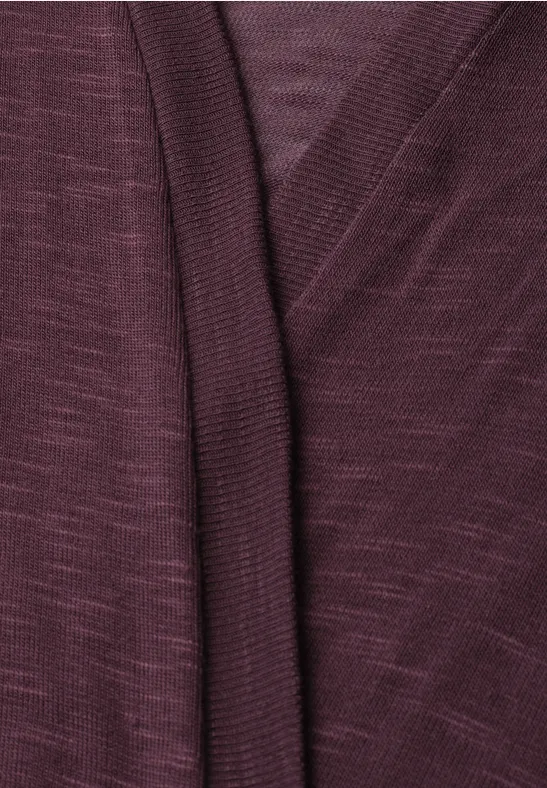Nahaufnahme eines burgunderroten Strickcardigans mit überlappendem V-Ausschnitt.