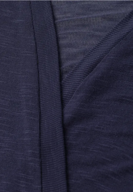Close-up van een donkerblauwe, fijne tricotstof met overlappende randen.