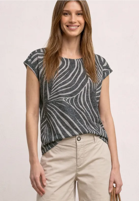 Vrouw met grijs, gemerkt T-shirt en beige broek, ze houdt een gouden smartphone in haar hand.